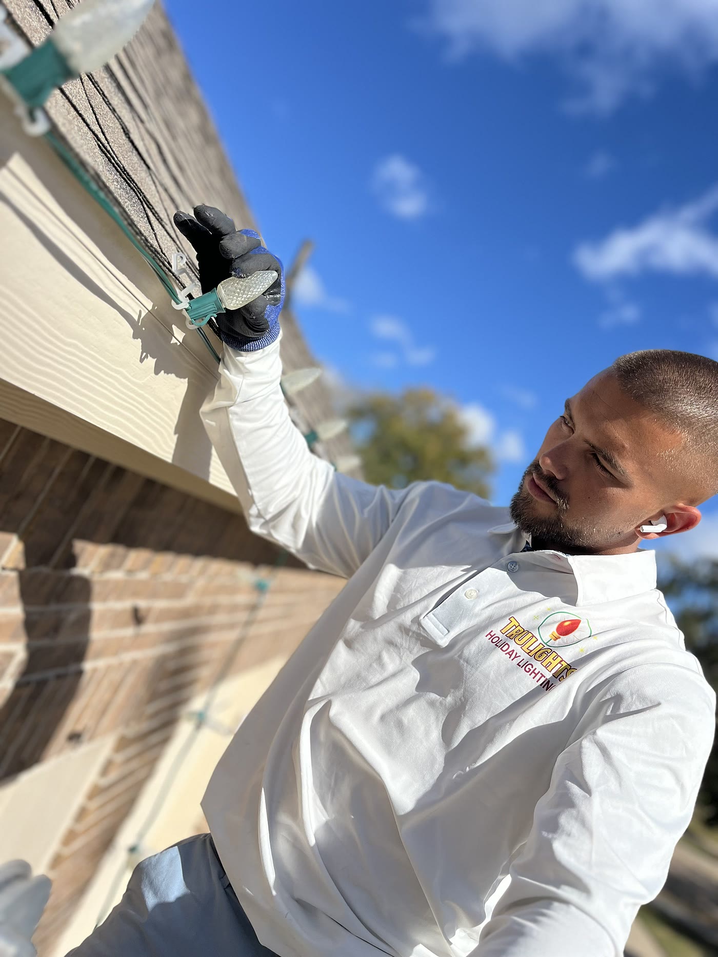TruLights installer in a company polo seating a bulb into the track along a fascia board